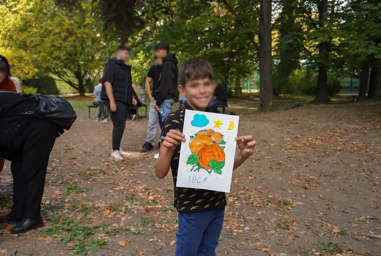 Un copil prezintă desenul său cu dovleci la atelierul de toamnă